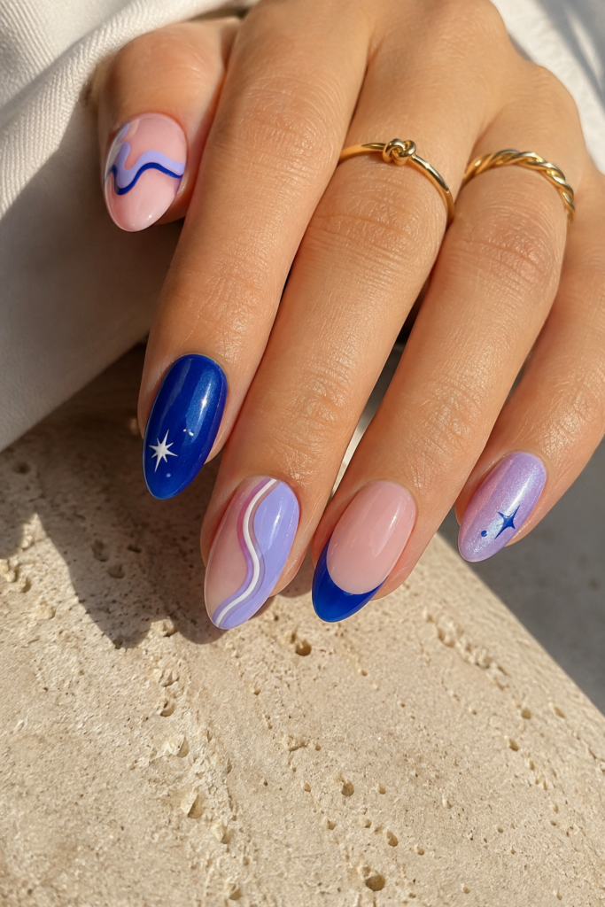 Glossy mismatched nails with cobalt, lilac, blush, stars, and playful swirls